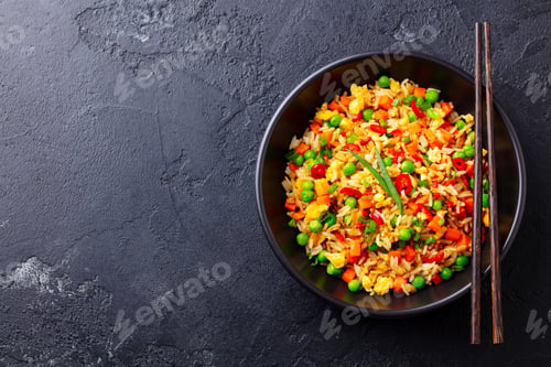 Preview: Asian fried rice with egg and vegetables. Black background. Cope space. Top view