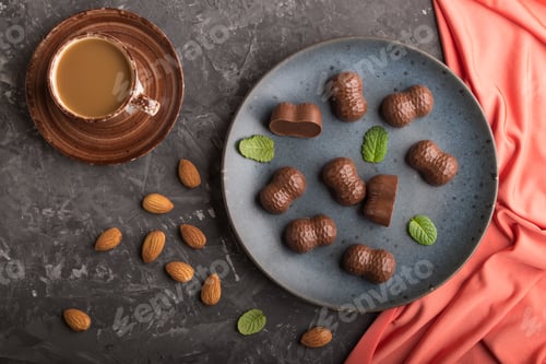 Vorschau: Pralinen mit Mandeln und einer Tasse Kaffee auf schwarzem Betonhintergrund. Ansicht von oben.