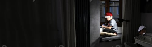 Preview: A boy in a santa claus hat writes a letter asking for a gift for Christmas. Dark room, Banner