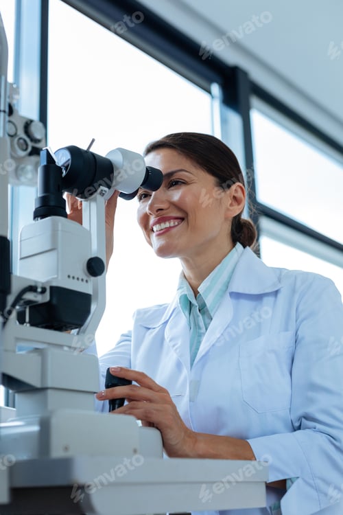 Preview: Cheerful female doctor looking into the microscope