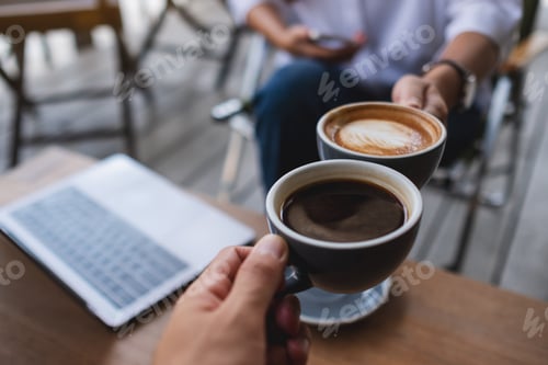 Preview: Two businessman clinking coffee cups together while working and meeting