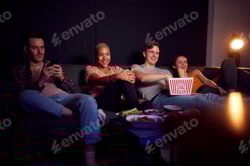 Preview: Man Using Mobile Phone Whilst Friends Watch TV At Home In Evening