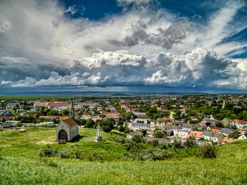 Preview: Scenic view of a church on a hill under a dramatic cloudy sky in Neusiedl am See, Austria