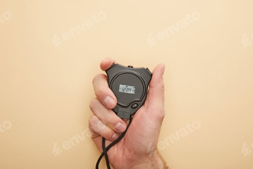 Preview: cropped view of man holding stopwatch on beige background