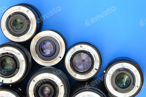 Preview: Several photographic lenses lie on a bright blue background. Space for text