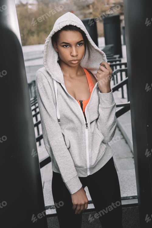 Preview: Attractive young fitness woman in sportswear standing and posing on stadium