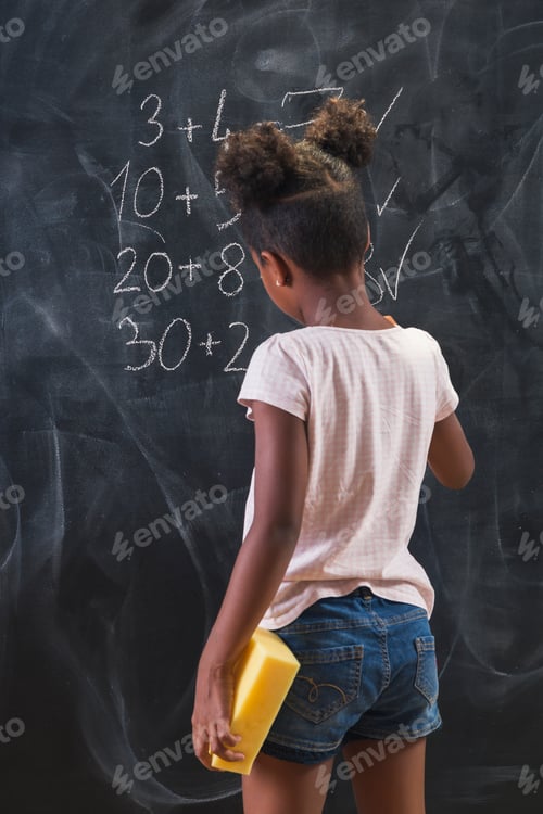 Preview: Mixed race elementary school girl doing math on chalkboard