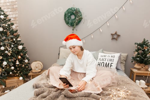 Preview: Girl in Santa Hat on Bed with Phone