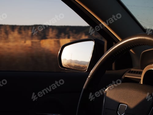 Preview: Golden evening light illuminating a car interior with a view of the steering wheel