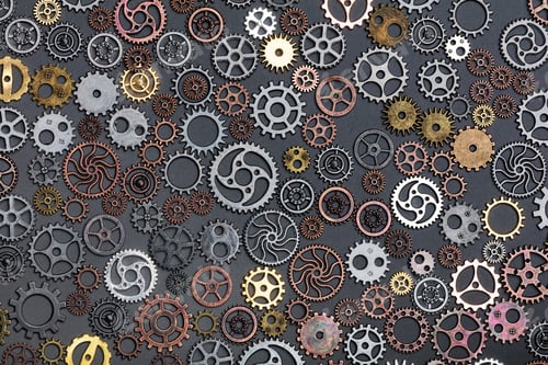 Preview: Different cogwheels laying on grey background.