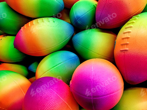 Preview: Footballs in a rainbow of colors for retail sale in a store.