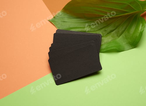 Preview: Piles of black paper empty business cards on orange-green background