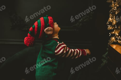 Preview: Little child under Christmas tree. baby boy in Santa Claus hat with gifts under Christmas tree with
