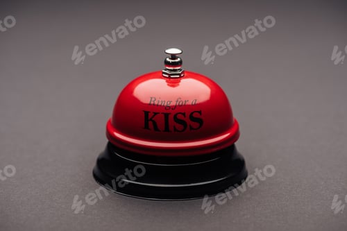 Preview: close up of red service bell with"ring for a kiss" lettering isolated on grey