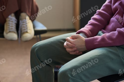 Preview: Young Man Sitting with Hands Clasped during Group Therapy