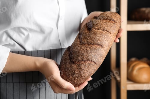 Preview: Baker holding loaf of bread indoors, closeup
