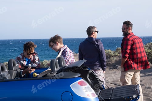 Preview: happy friends at the beach prepare to go to surf - couple of teenagers on car talking and laughing