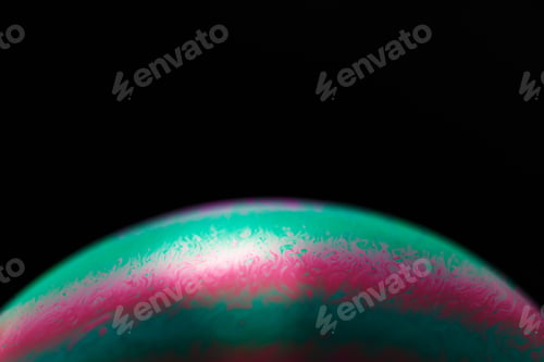 Preview: Rainbow soap bubble on a black background. Close-up of a colorful surface.