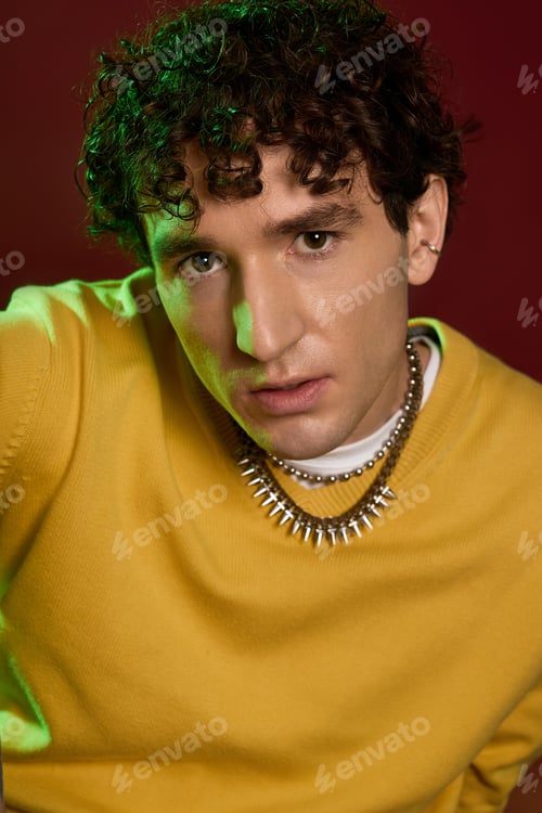 Preview: Stylish man exudes charm in vibrant outfit against bold backdrop