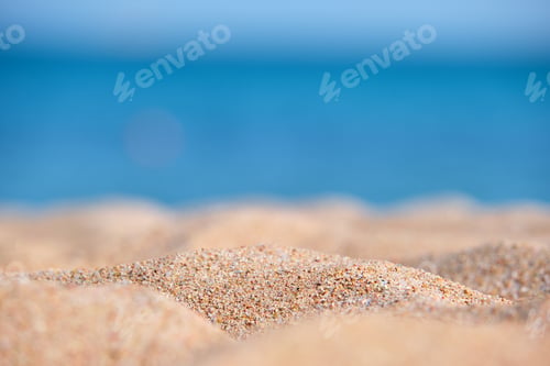 Preview: Close up of clean yellow sand surface covering seaside beach with blue sea water on background