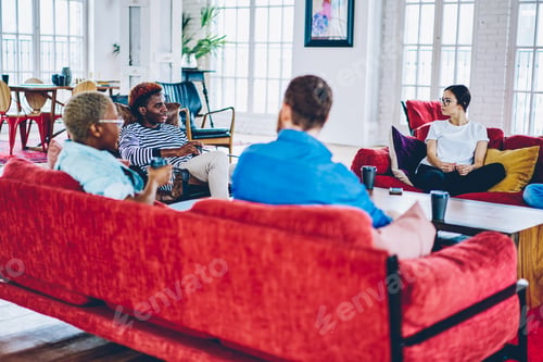 Preview: Multiracial group of hipsters having friendly conversation during meeting at apartment on leisure ti