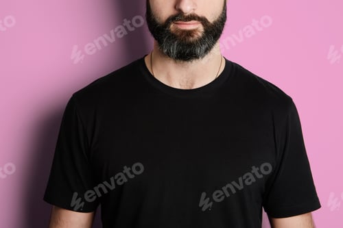 Preview: Portrait of bearded man in black tshirt on the empty pink background