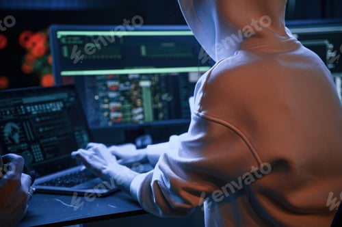Preview: Young professional female hacker is indoors by computer with lot of information on displays