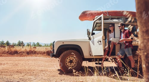 Preview: Young couple on road trip reading map for directions