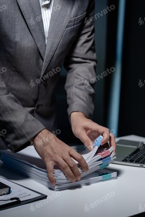 Preview: An employee was tidying up a pile of documents piled on his desk before returning home from work, A