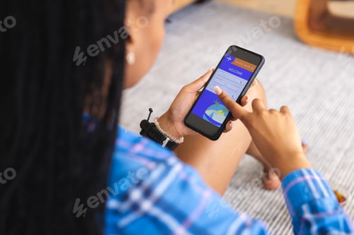 Preview: Young African American woman uses a smartphone, booking a vacation online