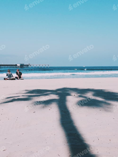 Preview: A surfer couple relaxes after an early morning surf session as the morning sun casts a palm tree