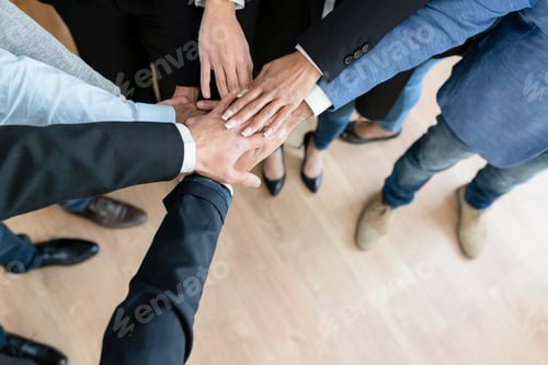 Preview: Unrecognizable business people holding hands standing in modern office, above view, teamwork concept