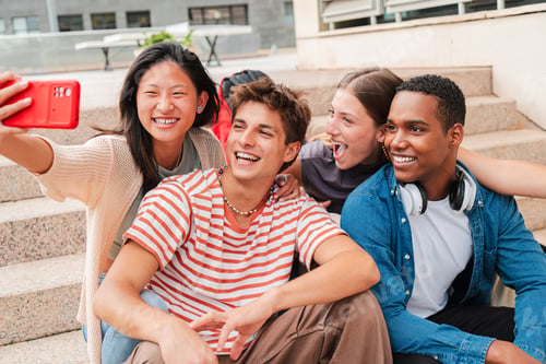 Preview: Group of international students taking a selfie portrait sitting on the university campus stairway