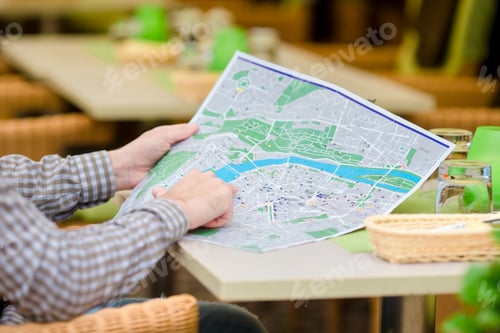 Preview: Caucasian young european man with citymap in outdoors cafe. Portrait of attractive young tourist on