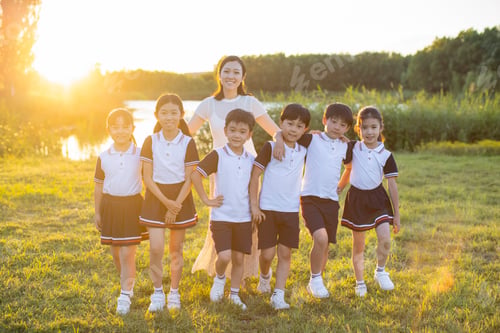 Preview: Cheerful Chinese school children relaxing in park with their teacher