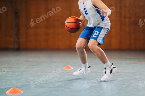Preview: Cropped image of junior basketball player dribbling a ball on training.