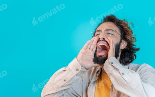 Preview: Man shouting loud calling attention with hands like megaphone isolated on blue studio background