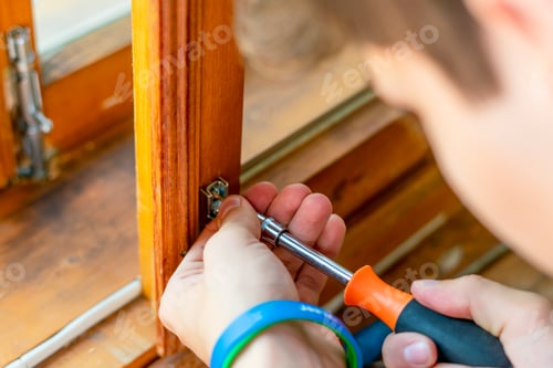 Preview: close up man hands working adjusting the steel bolt latch on a wooden window f