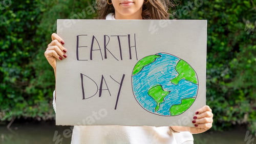 Preview: Woman promoting sustainability with a "Earth day" sign by the river