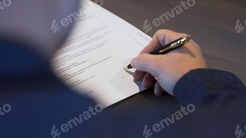 Preview: Rear view of a businessman in black shirt signing contract. Stock. Man putting his signature on