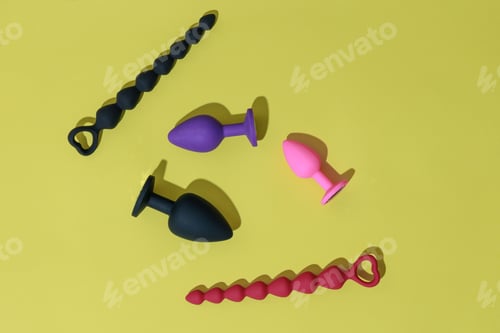 Preview: Top view of buttplugs and dildos for anal sex on yellow background with shadows. Sex