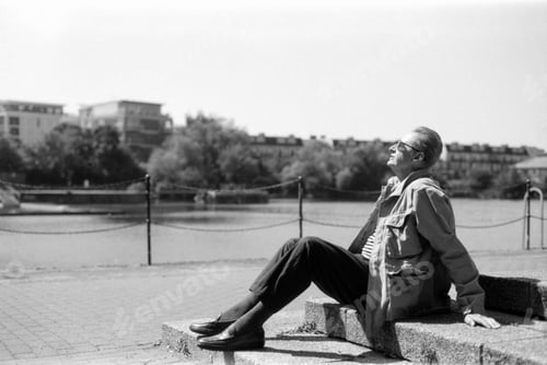 Preview: Senior man relaxing by the river in black and white analog film style