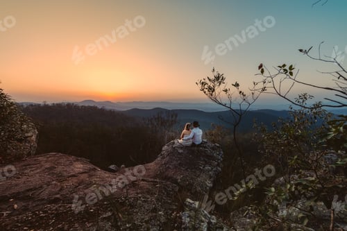 Preview: Couple Sitting Atop Rock Overlooking Mountainous Vista