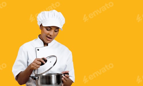 Preview: Excited black female chef carefully looking into stainless steel pot
