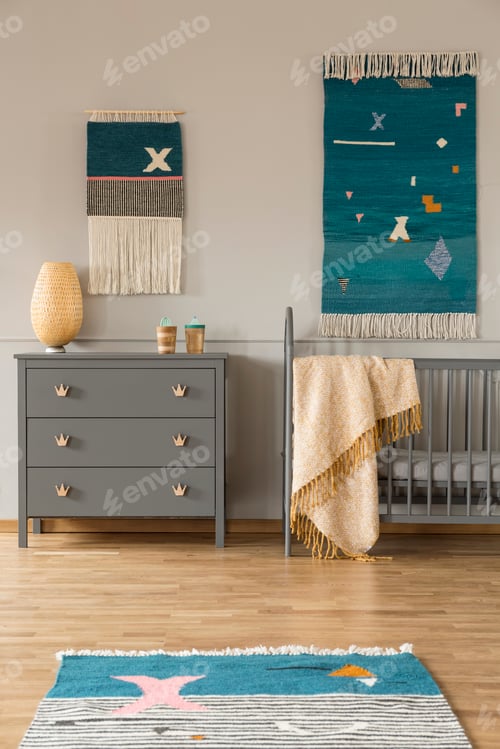 Preview: Decor on the wall above grey cabinet and child's bed with blanke