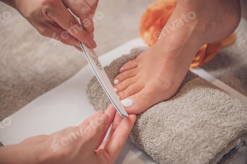 Preview: Closeup shot of a woman's hands pedicuring her client's foot.