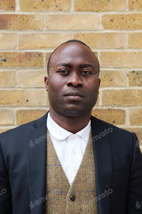Preview: Stylish Man Locks Eyes with the Camera Against a Brick Wall