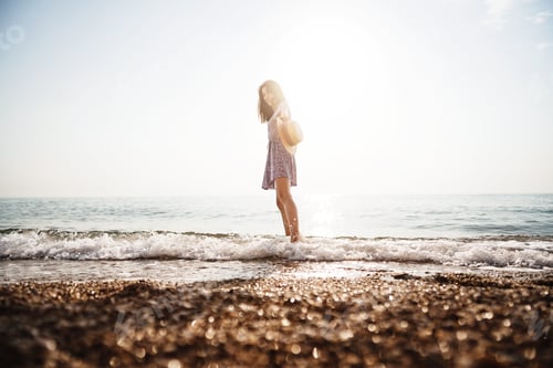 Preview: Lonely young woman walks on the seashore at sunset