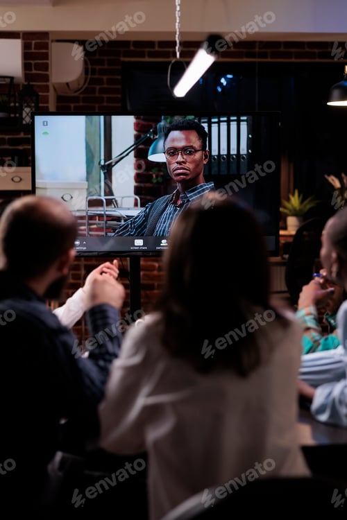 Preview: Diverse team working overtime late at night discussing with serious manager during online video call