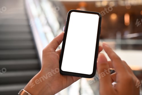 Preview: Close up view of woman hands holding smart phone on blurred escalator and flare effect background.